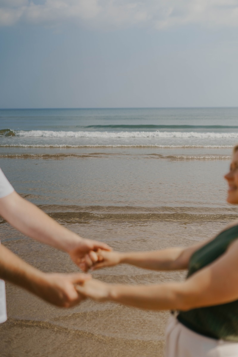 a man and a woman holding hands on the beach